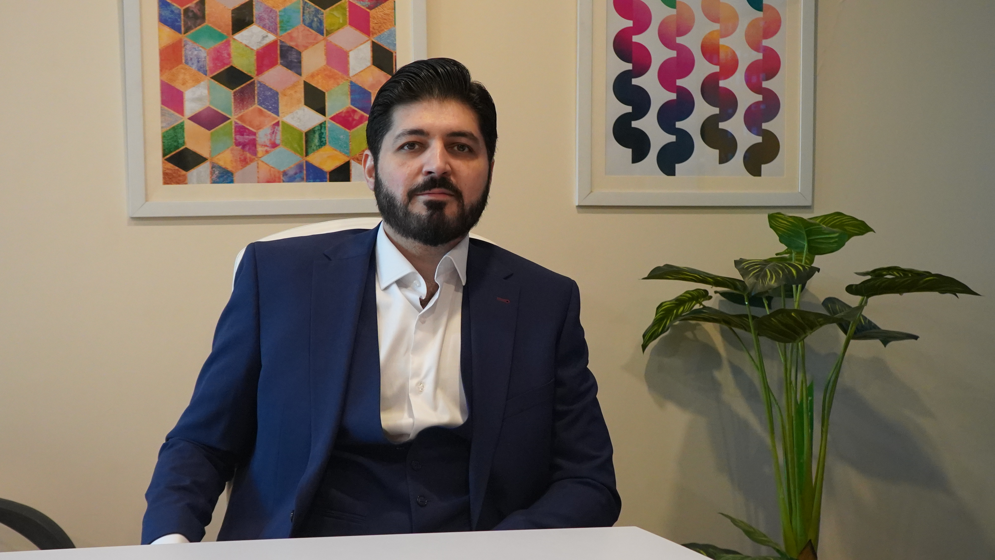 Shehryar T. Ali seated in his office; temporary television layout photograph.